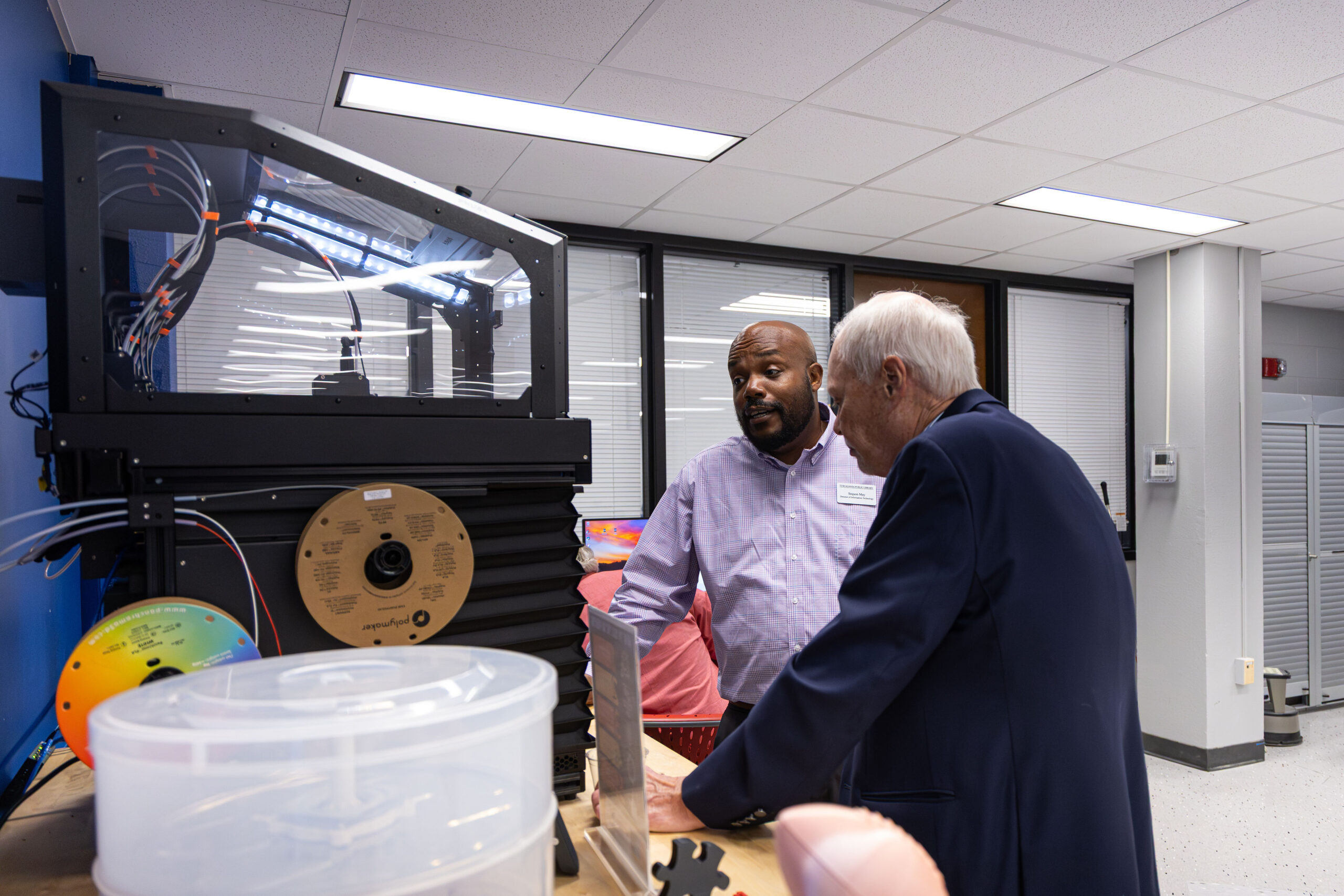 Staff member demonstrating the 3D printer to a visitor of the library