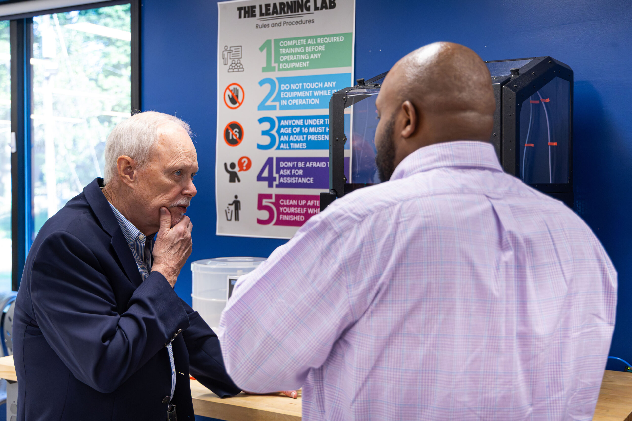 A TPL staff member talking with a donor while standing in front of a 3D printer