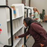 Individual looking at books on a shelf