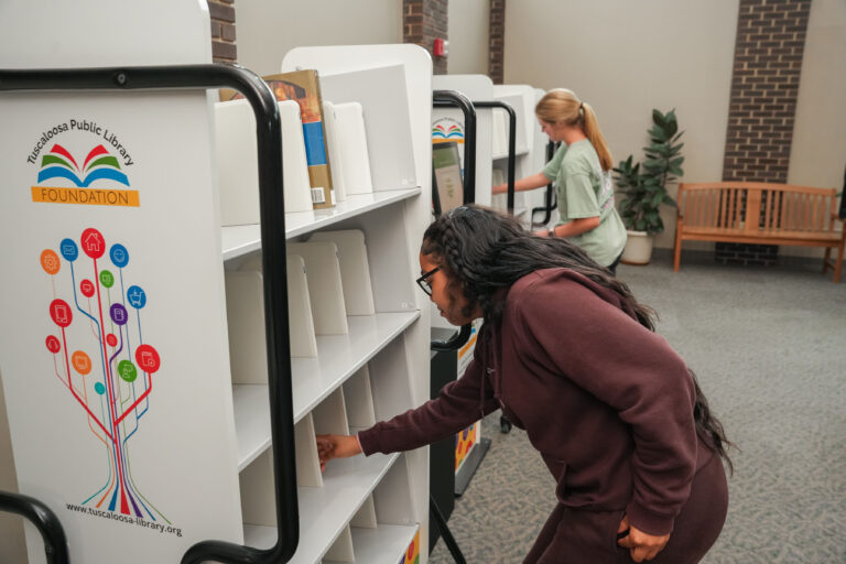 Individual looking at books on a shelf