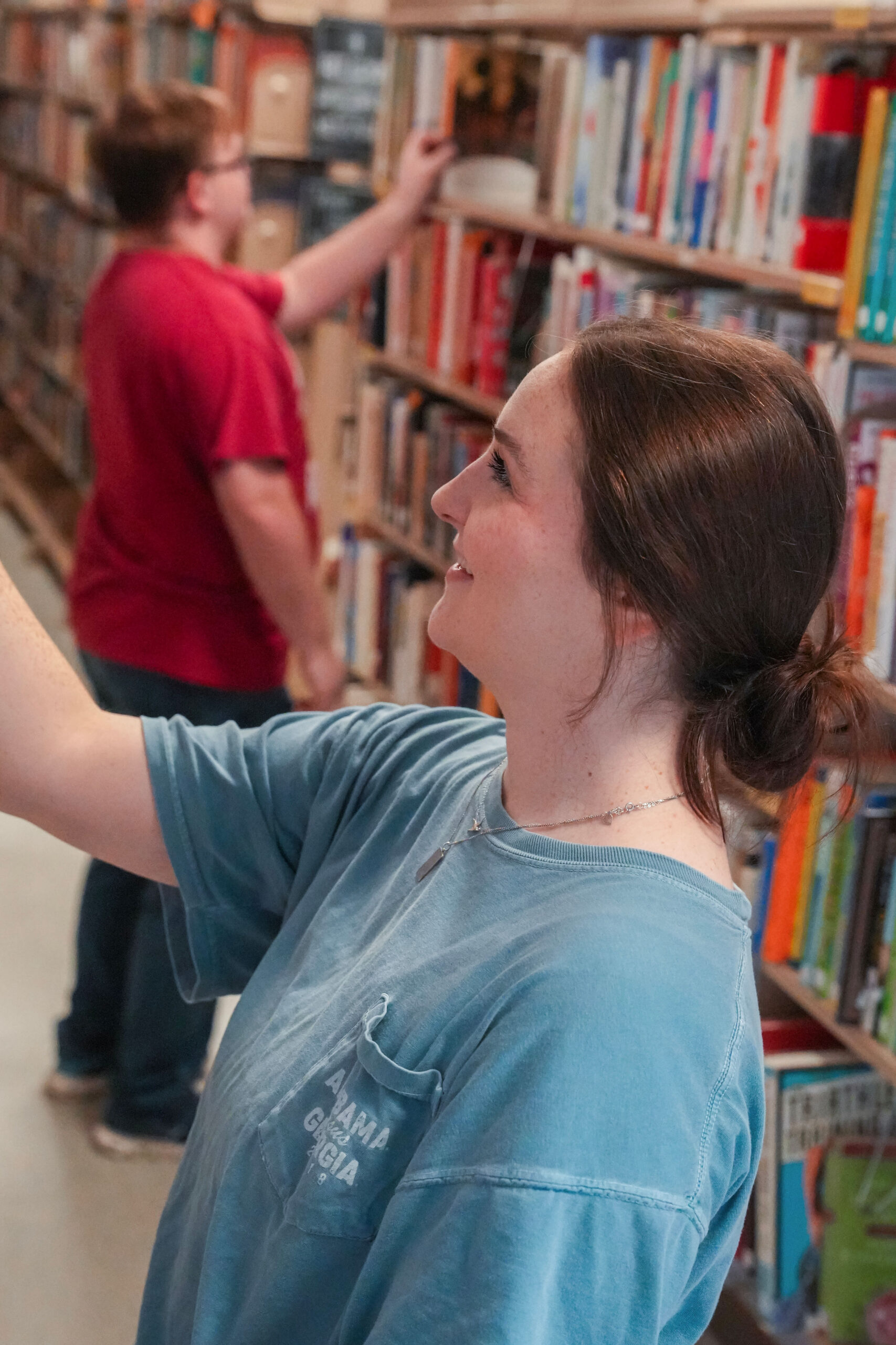 People standing in front of library bookshelves, reading book titles.
